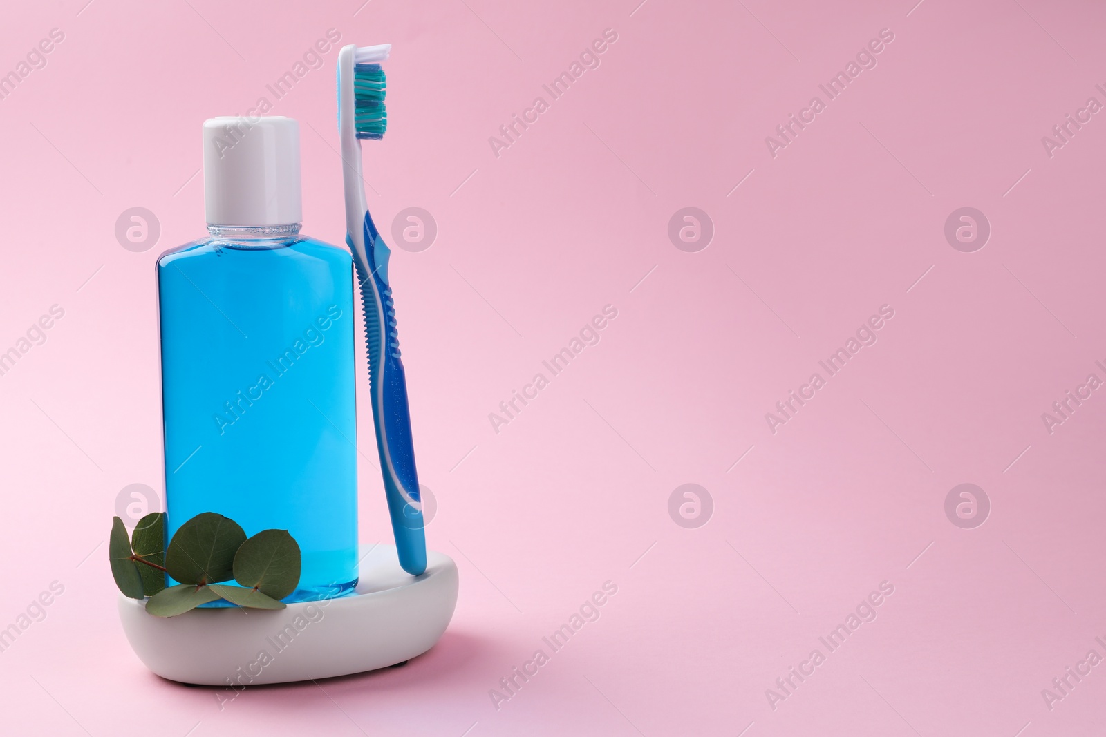 Photo of Fresh mouthwash in bottle and toothbrush on pink background, closeup. Space for text