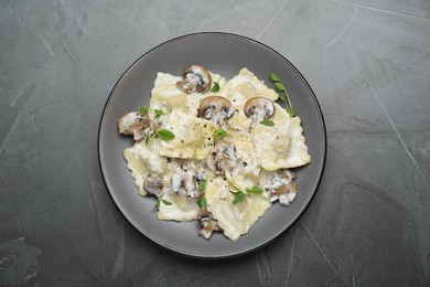 Photo of Delicious ravioli with tasty sauce and mushrooms on black table, top view