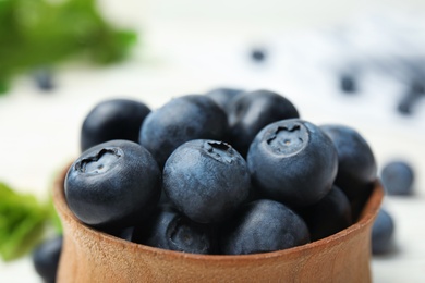 Photo of Wooden bowl with tasty blueberries on table, closeup