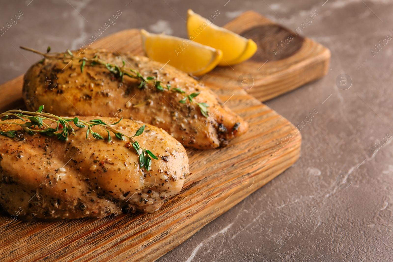 Photo of Baked lemon chicken with thyme served on grey marble table. Space for text