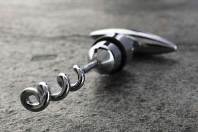 Photo of One metal corkscrew on grey textured table, closeup