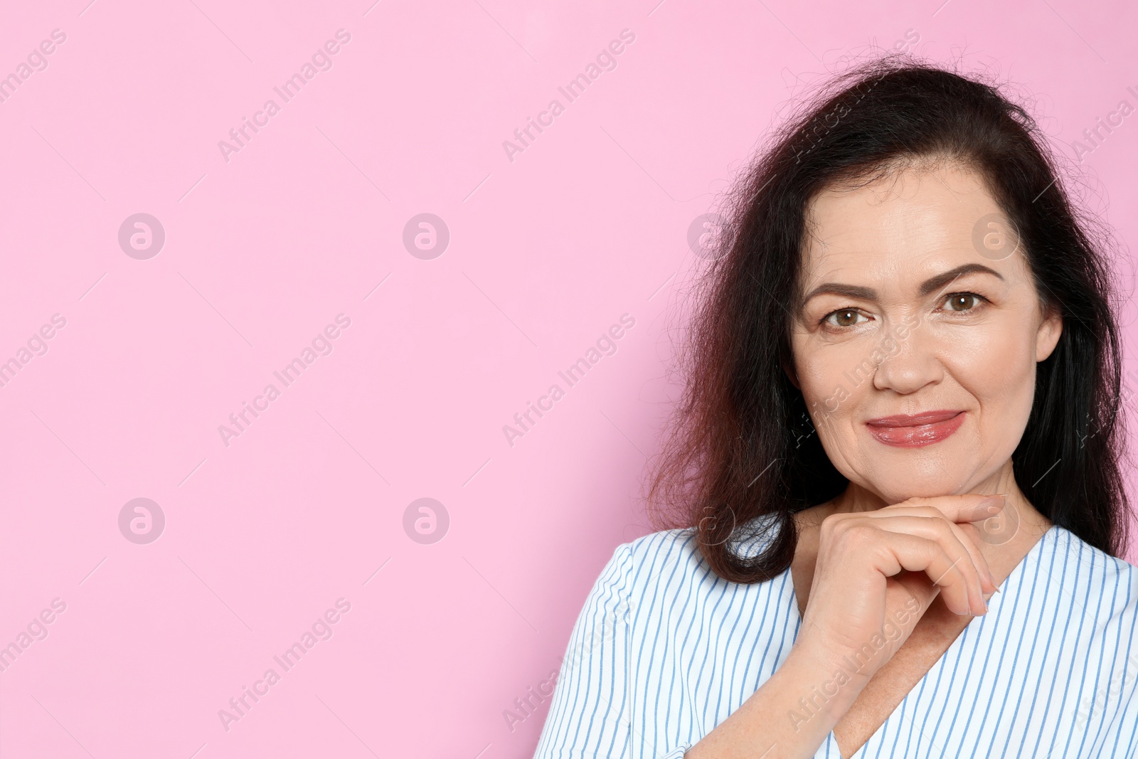 Photo of Portrait of mature woman with beautiful face on pink background. Space for text