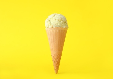 Delicious ice cream in waffle cone on yellow background