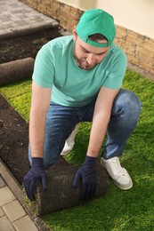 Photo of Worker laying grass sod on ground at backyard