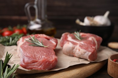 Fresh raw meat with rosemary on wooden board, closeup