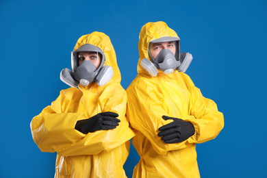 Photo of Man and woman wearing chemical protective suits on blue background. Virus research