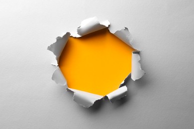 Photo of Hole in white paper on yellow background