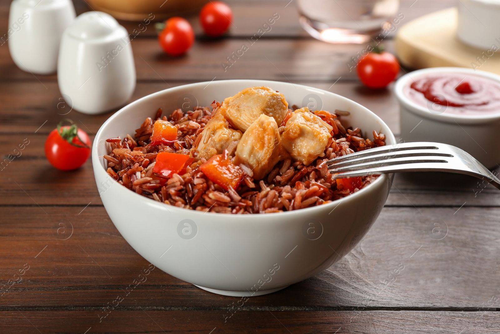 Photo of Delicious brown rice in bowl on wooden table