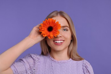 Beautiful woman with spring flower in hand on purple background