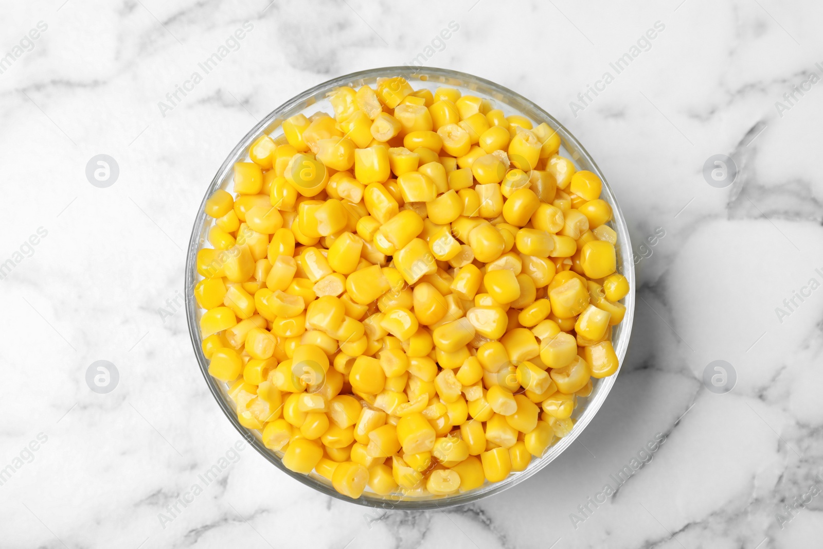 Photo of Delicious canned corn in bowl on marble table, top view