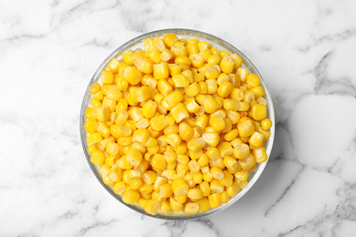 Photo of Delicious canned corn in bowl on marble table, top view