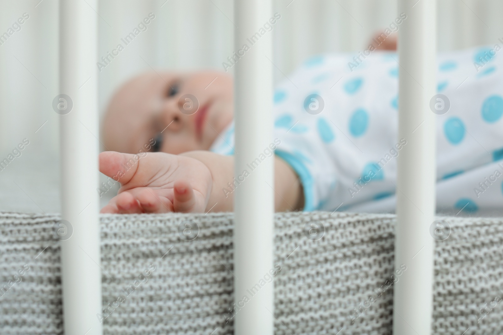 Photo of Cute little baby lying in crib, closeup