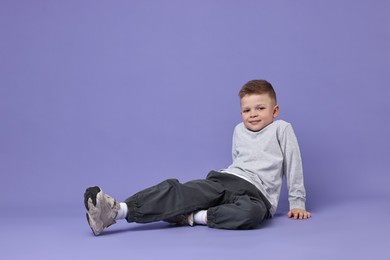 Happy little boy dancing on violet background