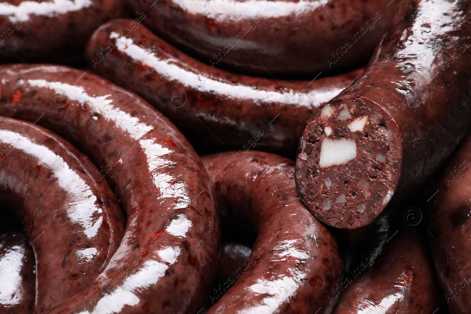 Photo of Cut and whole tasty blood sausages as background, closeup view
