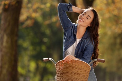 Photo of Young woman with bicycle in autumn park, space for text
