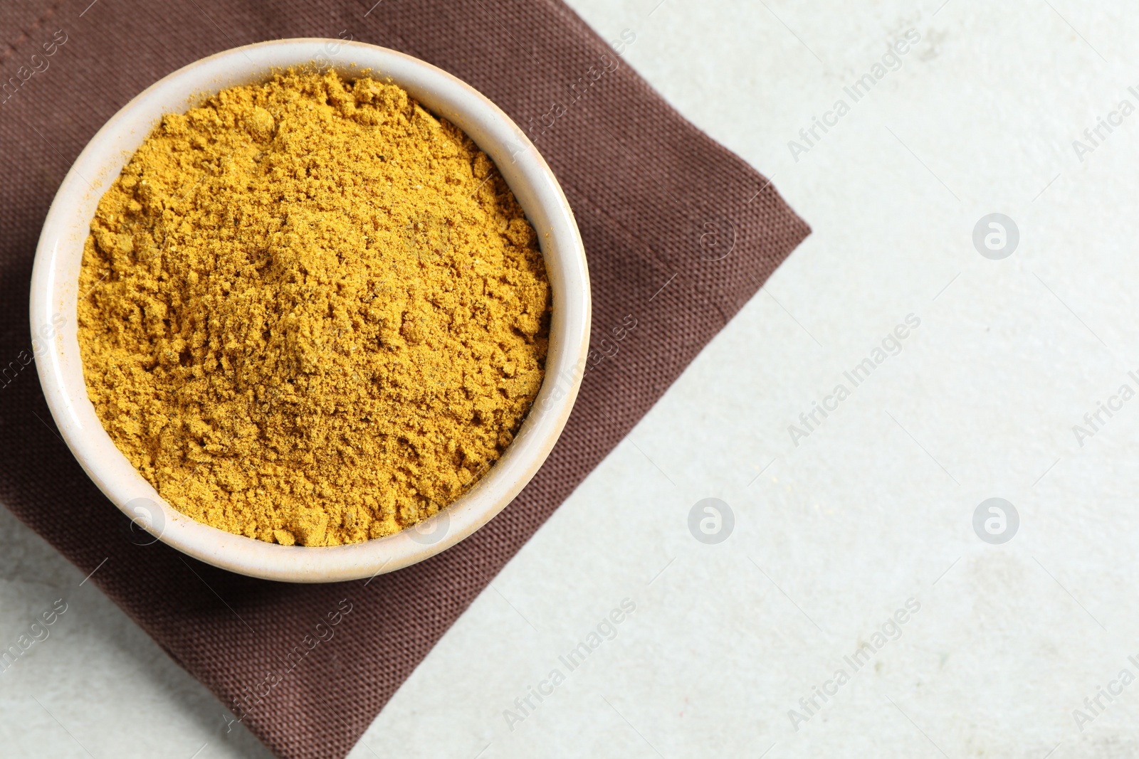 Photo of Curry powder in bowl on white table, top view. Space for text