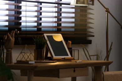Stylish workplace with modern tablet on table at window. Ideas for interior design