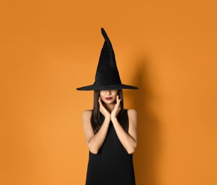 Photo of Beautiful woman wearing witch costume for Halloween party on yellow background, space for text