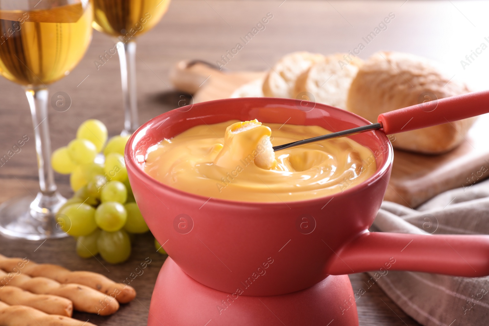 Photo of Pot with delicious cheese fondue and bread on table