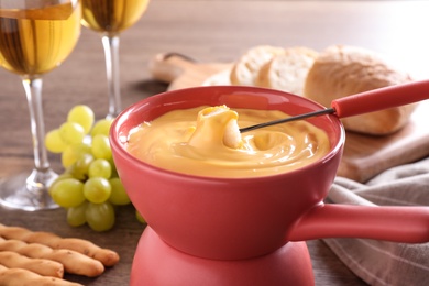 Photo of Pot with delicious cheese fondue and bread on table