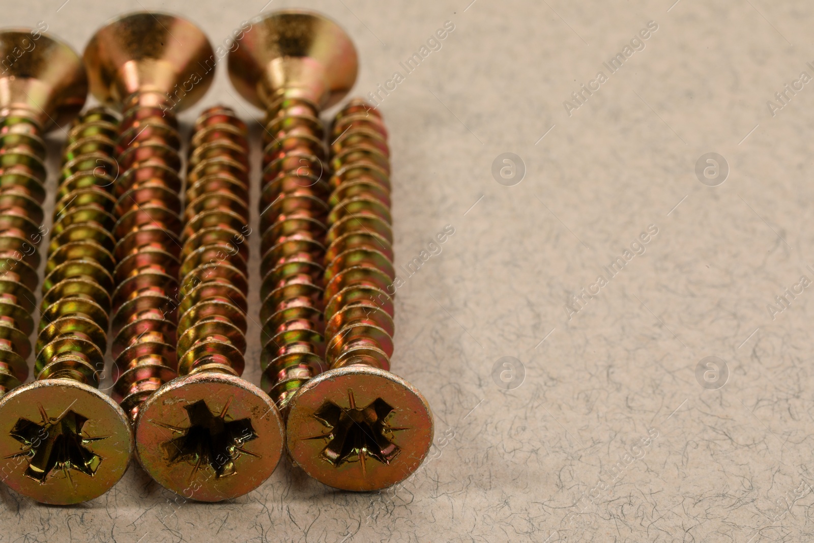 Photo of Many metal screws on beige background, closeup. Space for text