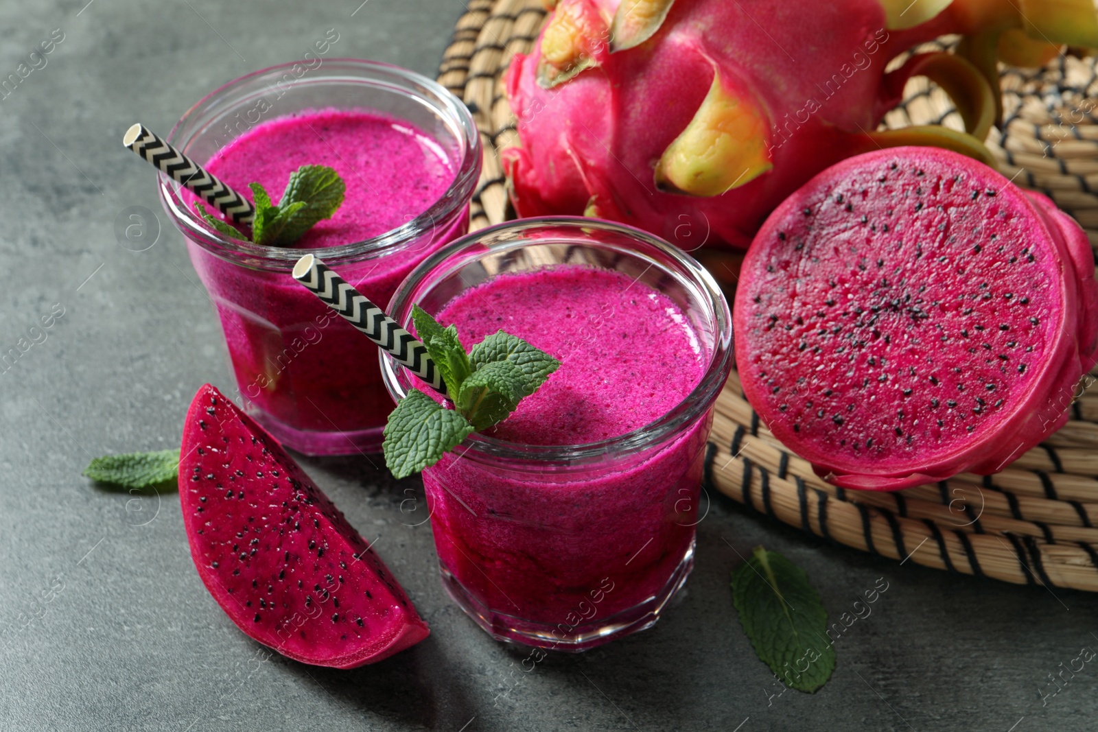 Photo of Delicious pitahaya smoothie, fruits and fresh mint on grey table