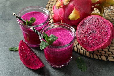 Photo of Delicious pitahaya smoothie, fruits and fresh mint on grey table