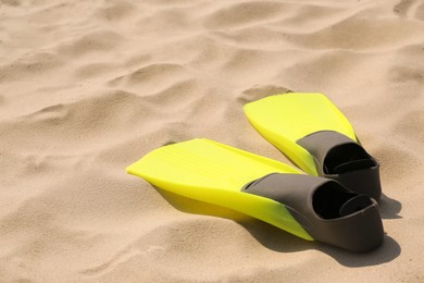 Photo of Pair of yellow flippers on sand. Space for text