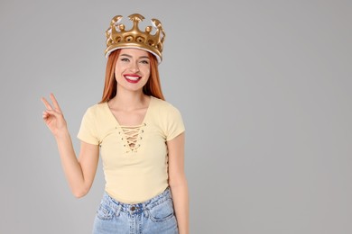 Photo of Beautiful young woman with inflatable crown on light grey background, space for text