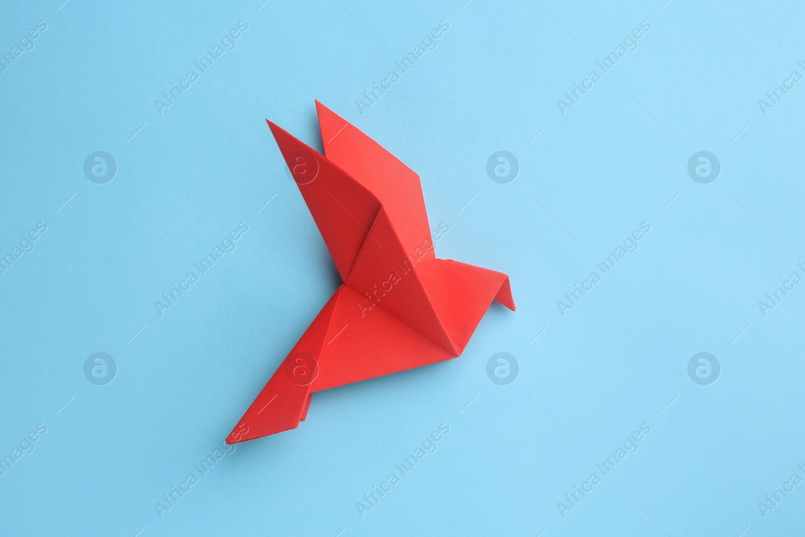 Photo of Origami art. Beautiful handmade paper bird on light blue background, top view