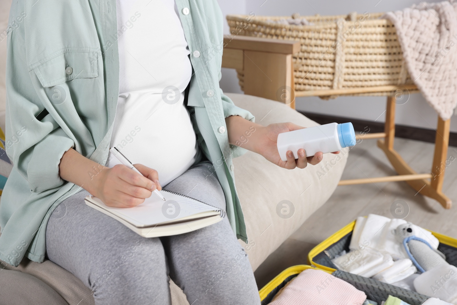 Photo of Pregnant woman preparing list of necessary items to bring into maternity hospital at home, closeup