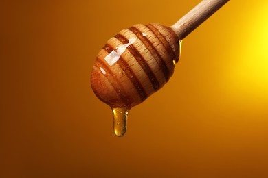 Photo of Pouring honey from dipper against golden background