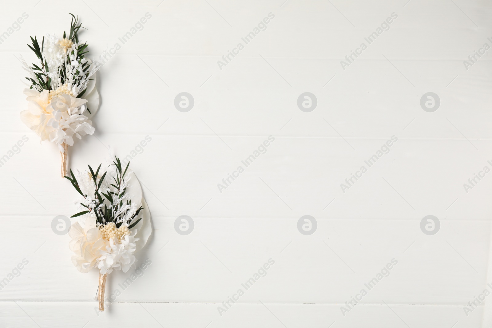 Photo of Beautiful boutonnieres on white background, flat lay. Space for text