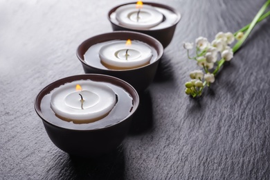 Photo of Burning candles in bowls with water on table