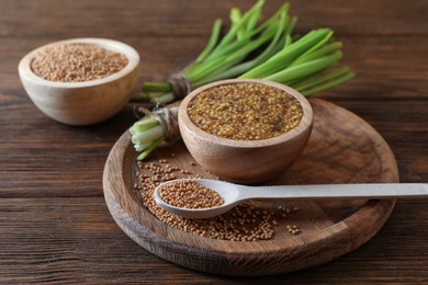 Tray with delicious whole grain mustard, seeds and fresh green onion on wooden table