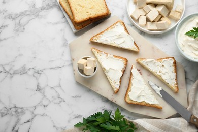 Photo of Delicious toasts with tofu cream cheese and parsley on white marble table, flat lay. Space for text