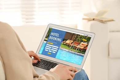 Image of Man using laptop to book hotel at home, closeup