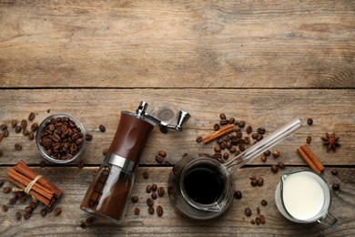 Photo of Manual coffee grinder with powder, beans, milk and jezve of drink on wooden table, flat lay. Space for text