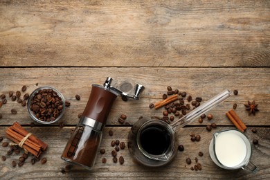 Manual coffee grinder with powder, beans, milk and jezve of drink on wooden table, flat lay. Space for text