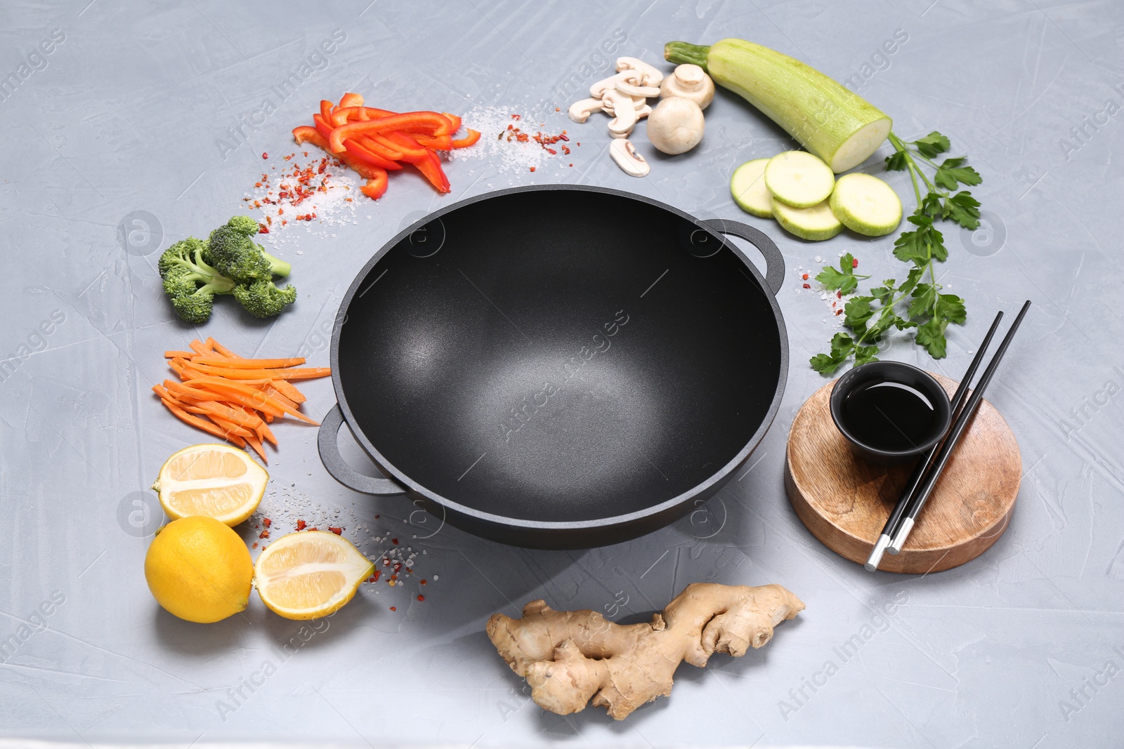 Photo of Wok, chopsticks and different products on grey table