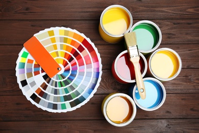 Photo of Flat lay composition with paint cans, brush and color palette on wooden background