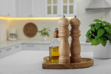 Photo of Wooden salt and pepper shakers, bottle of oil on white table indoors, space for text