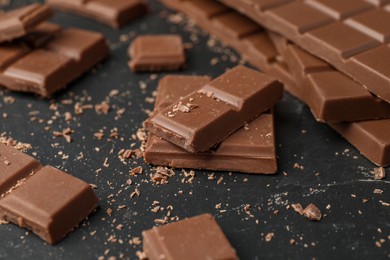 Photo of Pieces of tasty chocolate on dark table, closeup
