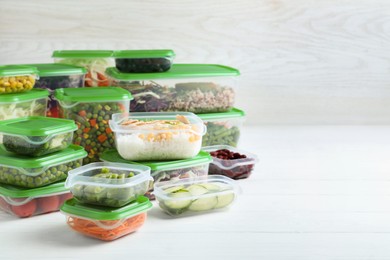 Photo of Set of plastic containers with fresh food on white wooden table, space for text