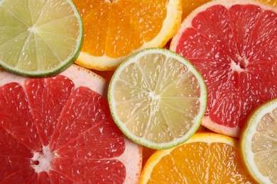 Slices of different citrus fruits as background, top view