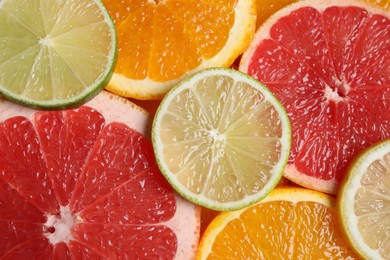 Photo of Slices of different citrus fruits as background, top view