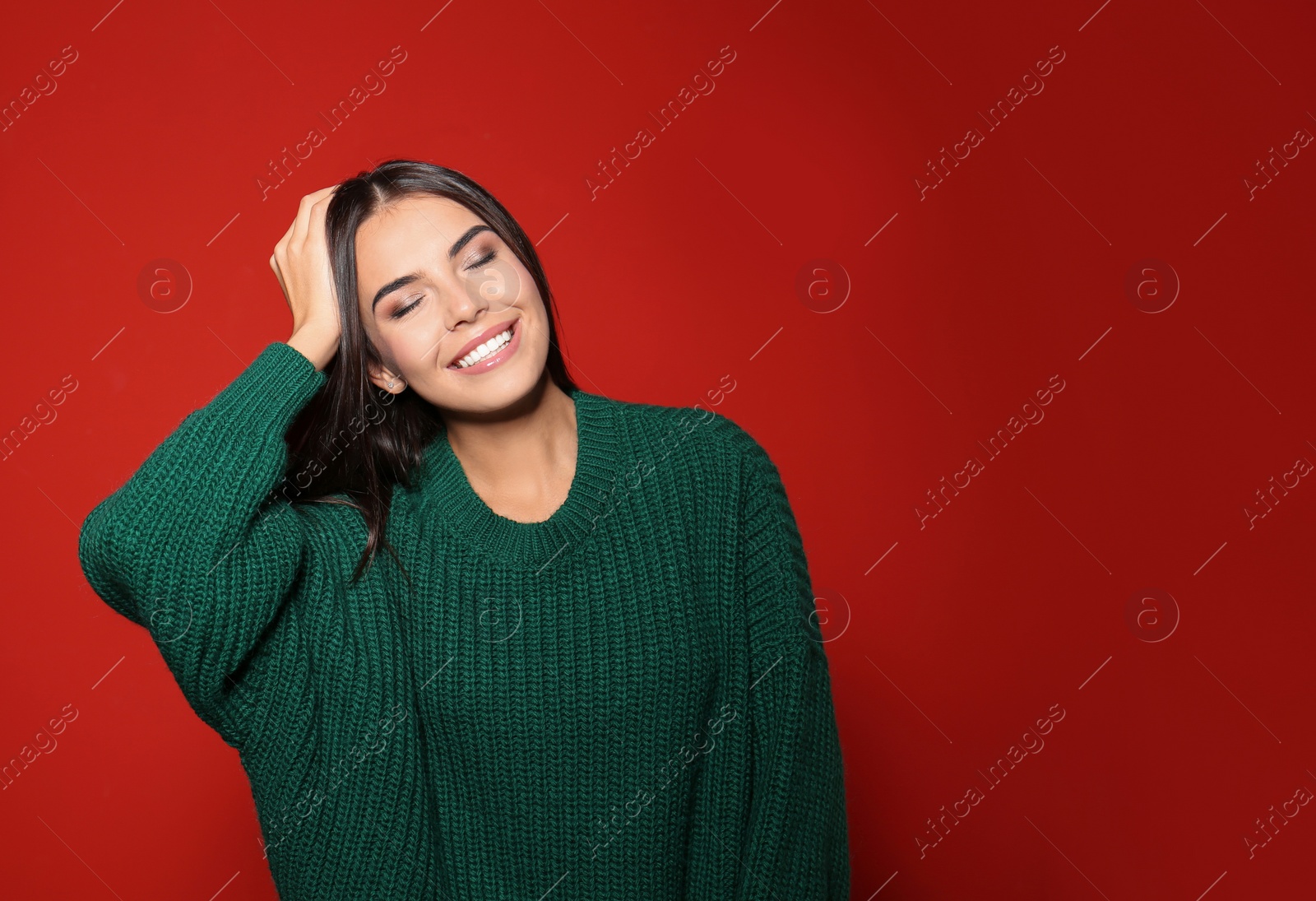 Image of Pretty woman wearing warm sweater on red background. Space for text