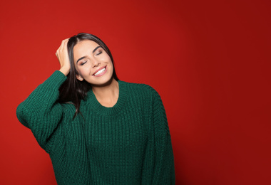 Pretty woman wearing warm sweater on red background. Space for text