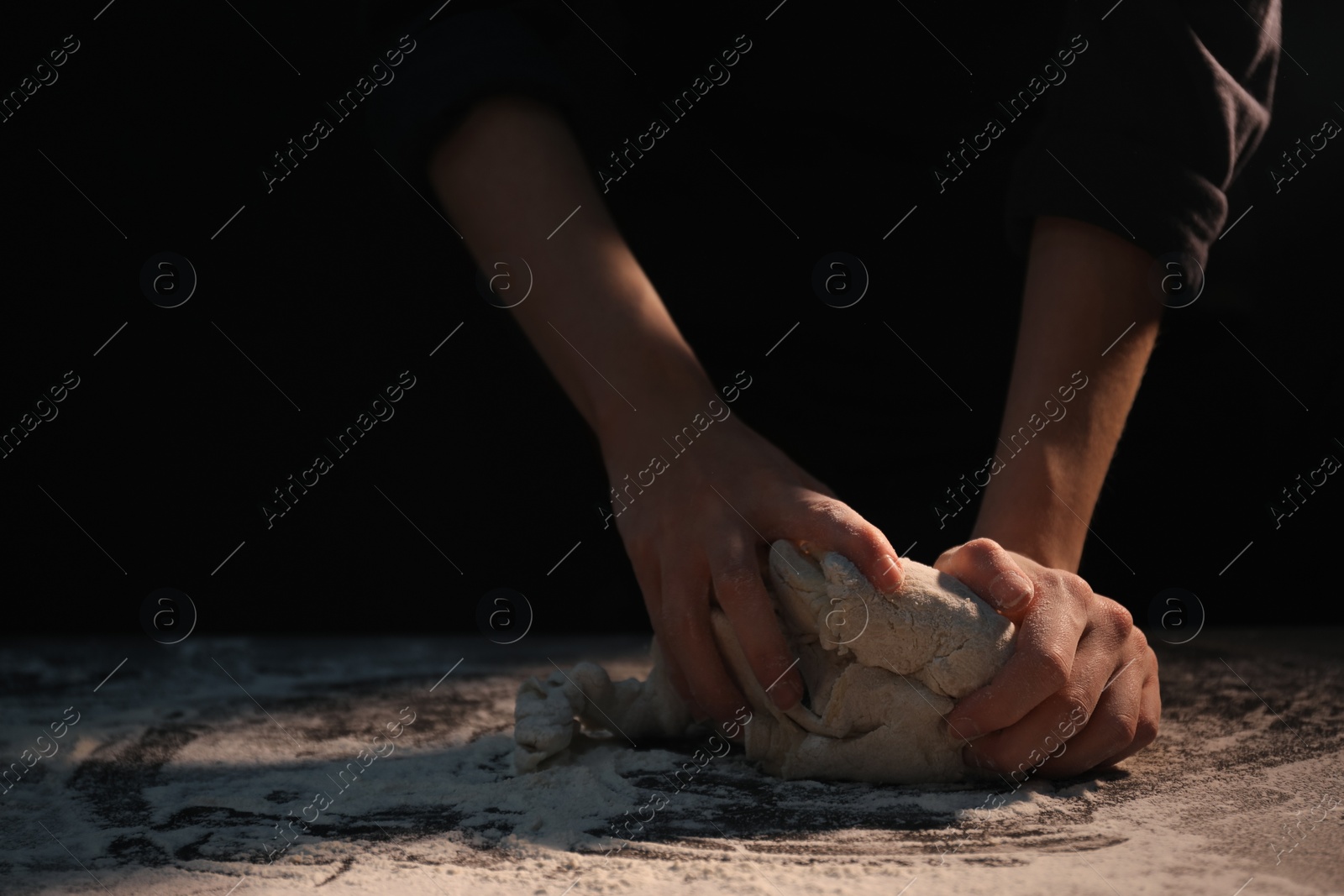 Photo of Making bread. Woman kneading dough at table on dark background, closeup. Space for text