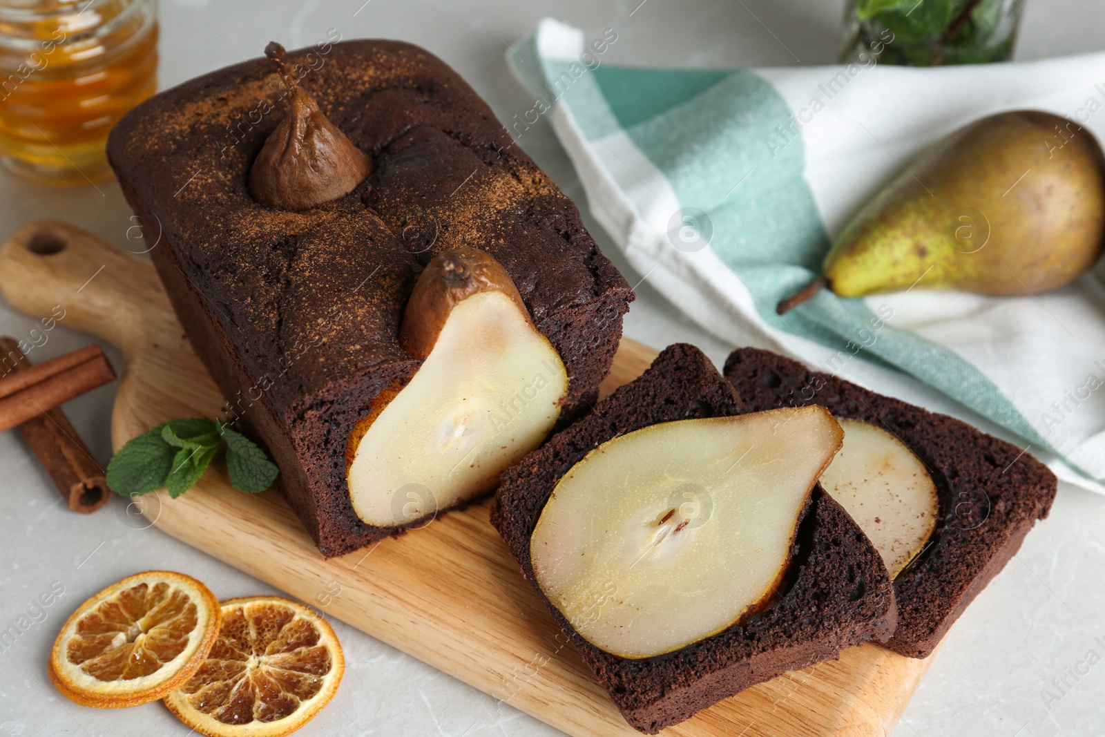 Photo of Tasty pear bread with mint, cinnamon and dried orange slices on table. Homemade cake